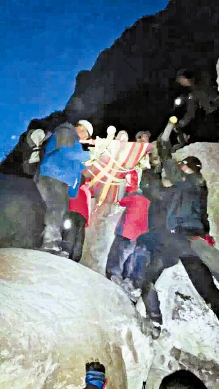 救援隊(duì)員用自制的簡(jiǎn)易擔(dān)架抬傷者。