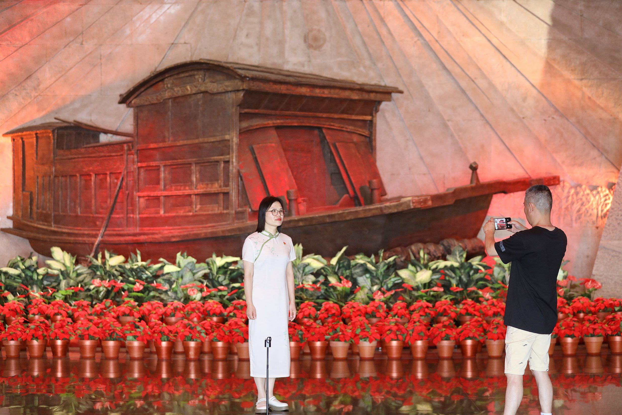 2025年6月24日，浙江嘉興，游客在南湖革命紀(jì)念館與紅船雕塑合影。（圖片來源：視覺中國(guó)）