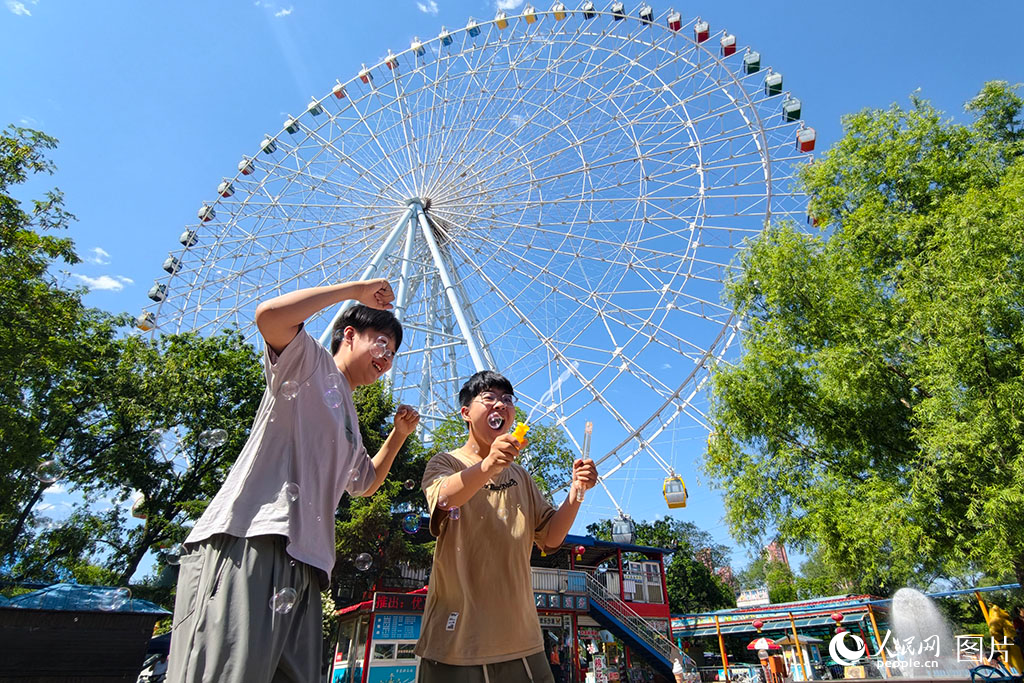 2026年5月30日，在遼寧沈陽(yáng)萬(wàn)泉公園，孩子們正在88米高的摩天輪下快樂(lè)地玩耍。人民網(wǎng)記者 周頌雪攝